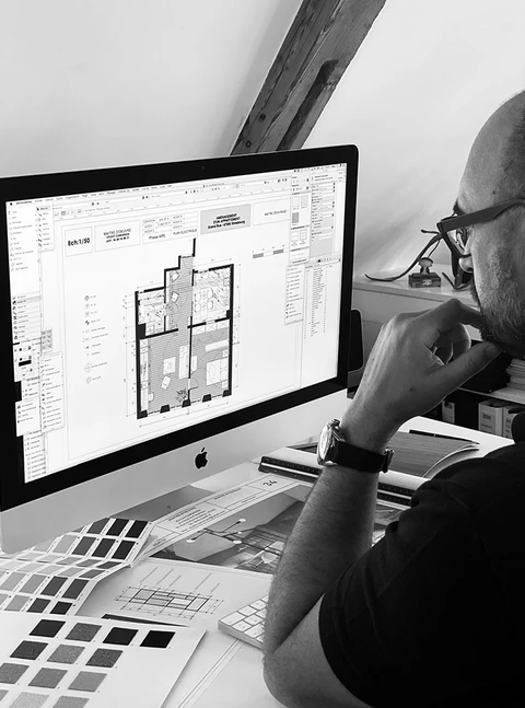 Architecte d'intérieur masculin, chauve, lunettes, concentré devant un iMac Apple