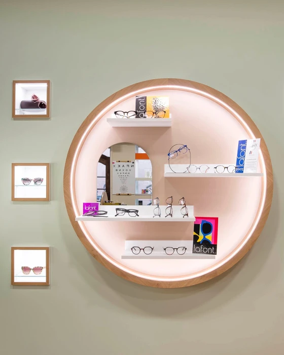 Boutique d'optique haut de gamme, présentoir circulaire rétroéclairé en bois naturel avec miroir arqué central