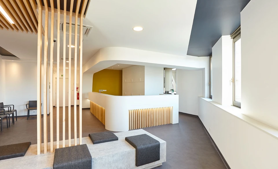 Espace d'accueil médical moderne avec comptoir de réception incurvé en Corian blanc, éclairage LED intégré en lame de bois
