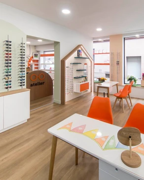 Intérieur d'un magasin d'optique moderne avec une femme floue en arrière-plan consultant des lunettes