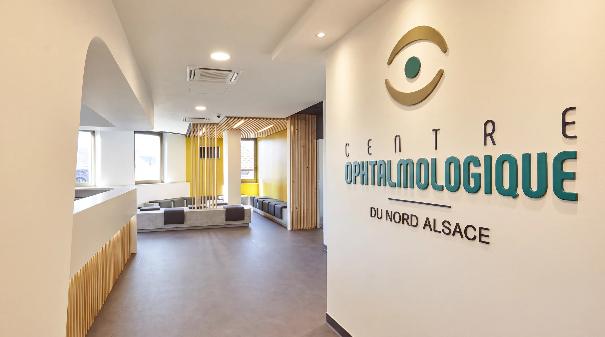 Accueil médical moderne avec comptoir de réception incurvé en Corian blanc, postes de travail équipés d'ordinateurs portables et imprimante multifonction